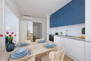Ett modernt kök med blå skåp, ett matbord för fyra personer och en vas med röda tulpaner.