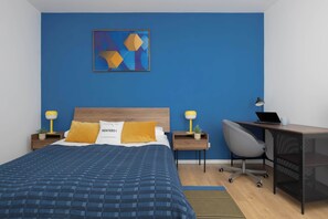 Ein Hotelzimmer mit einem Bett, einem Schreibtisch, einem Stuhl und einem Wandbild.