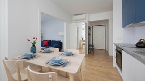 A modern kitchen with a dining area, wooden chairs, and a table set for four. - Stylish Apartment with Air Conditioning | Parking | Close to the City Centre (Warszawa)