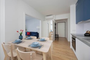 A modern kitchen with a dining area, wooden chairs, and a table set for four. - Stylish Apartment with Air Conditioning | Parking | Close to the City Centre (Warszawa)