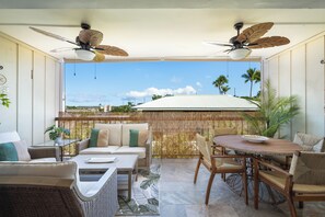 Eine sonnendurchflutete Terrasse mit Esstisch, Stühlen und einer Couch.