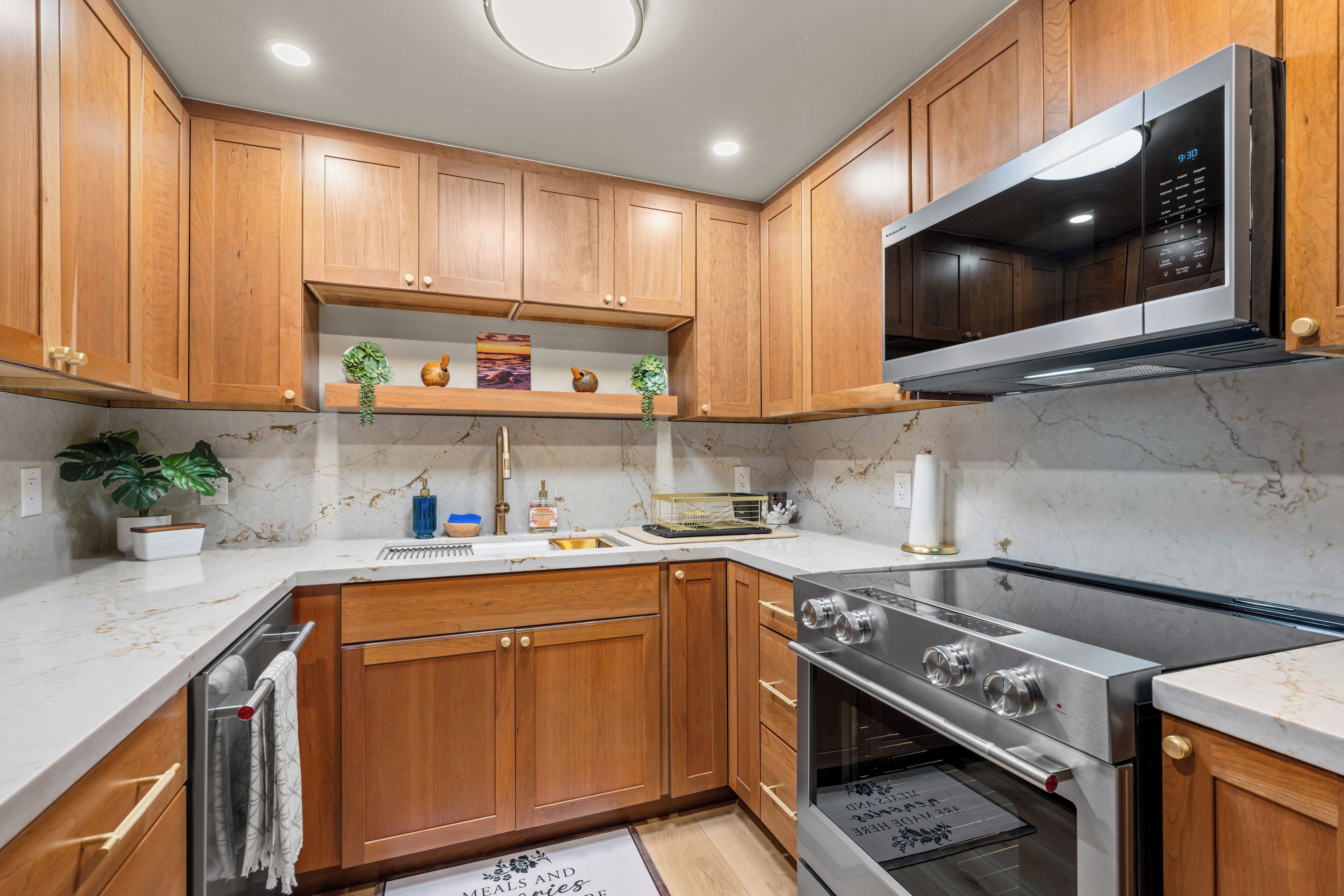 A modern kitchen with wooden cabinets, stainless steel appliances, and a marble countertop.