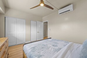 Ein Schlafzimmer mit einem Bett, einem Deckenventilator und einer Klimaanlage.