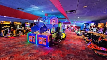 Een overdekte speelhal met diverse spelautomaten, een gekleurd tapijt en een plafond met rasterwerk.