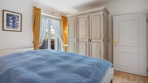 Un dormitorio con cama, puerta y ventana con cortinas.