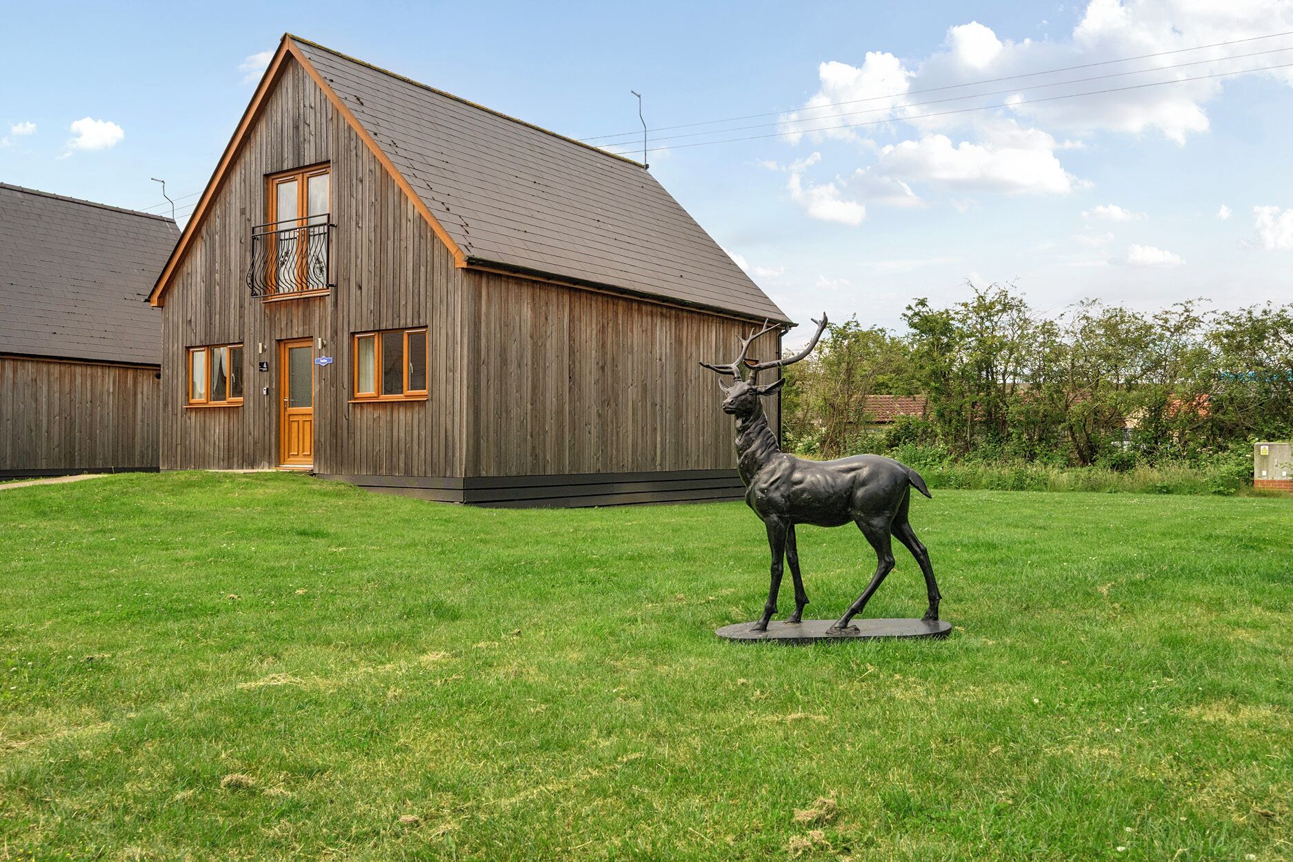 A wooden building with a sloped roof and a statue of a deer in front.