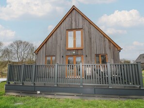 Ein Holzhaus mit Satteldach, einer Veranda und einer umzäunten Terrasse.