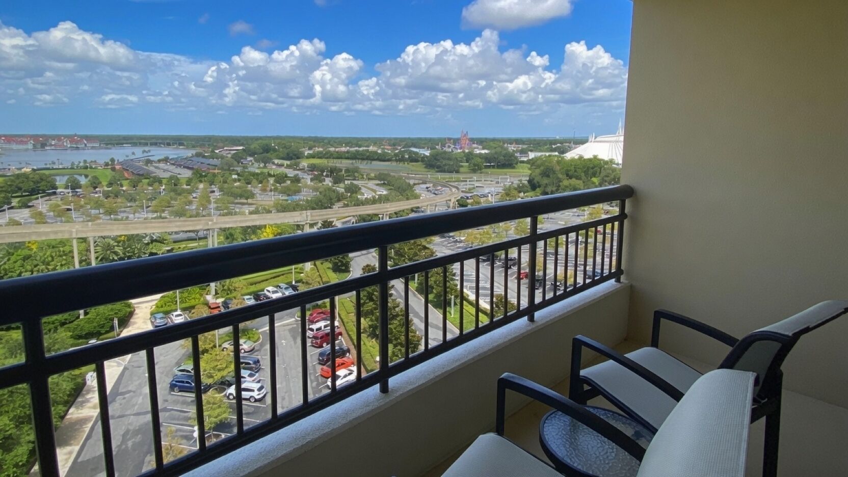 A balcony with a view of a parking lot and a body of water.