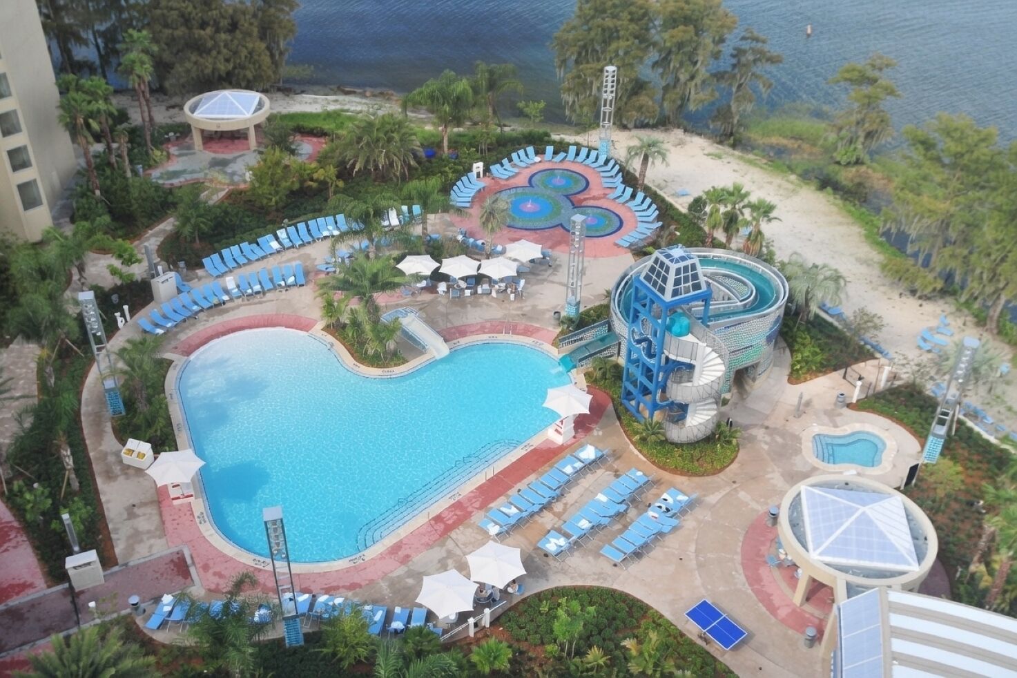 A resort with a large central pool, a water slide, and multiple sun loungers.