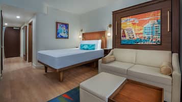 Ein Hotelzimmer mit Bett, einer Couch, einem Gemälde und Holzboden.