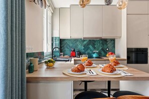 Eine moderne Küche mit Frühstücksbereitstellung, darunter Croissants, Orangensaft und ein Wasserkocher.