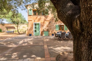 A two-story building with a patio area, outdoor seating, and a swing. - Rural house 'Ses Rotetes' with private pool, terrace, and private garden (Manacor)