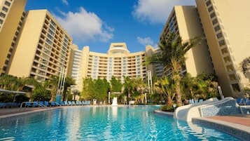 Un hotel con piscina, palme e un cielo azzurro limpido.
