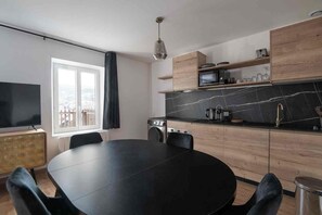 Une cuisine moderne avec une table à manger ronde, des appareils électroménagers intégrés et une grande fenêtre.
