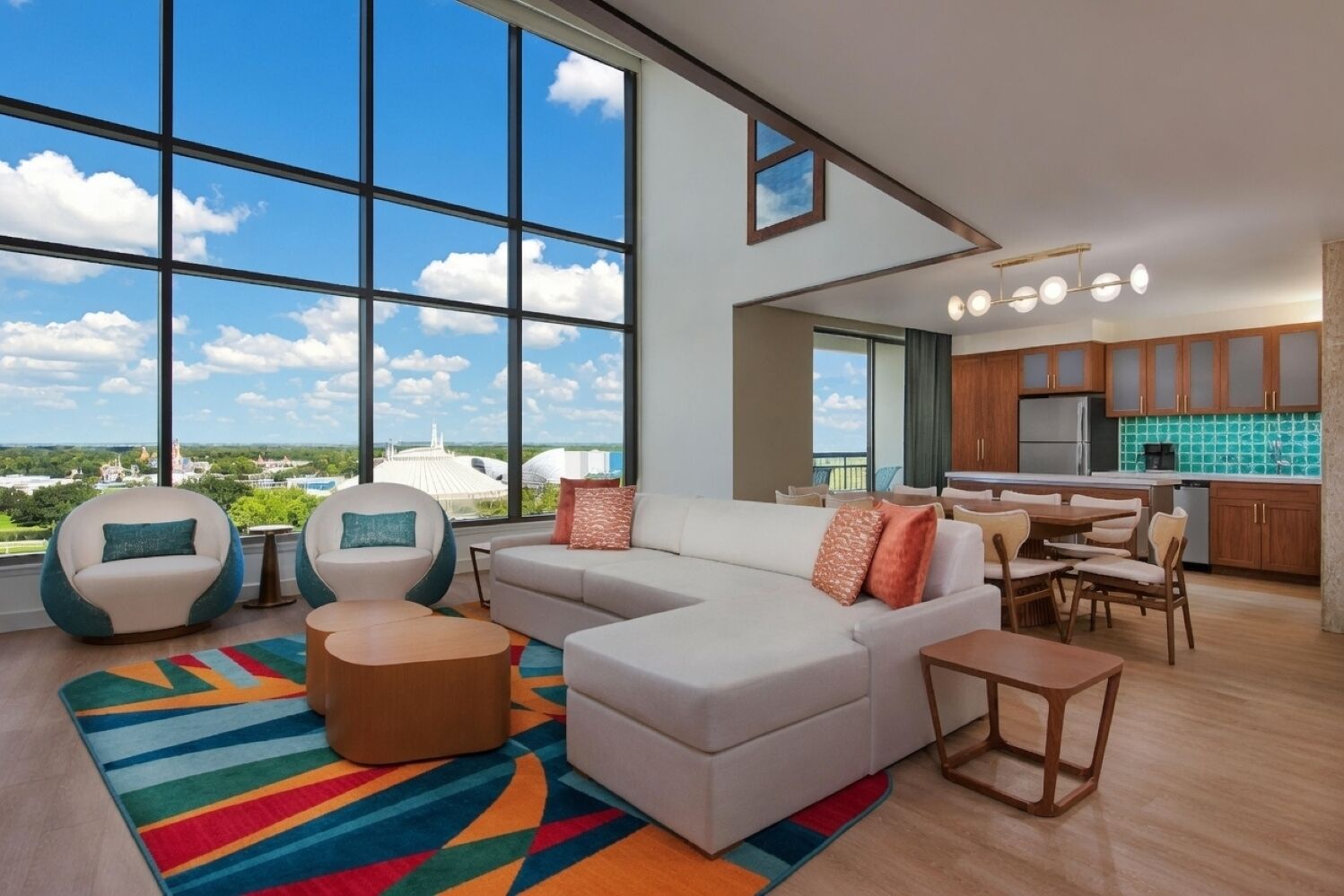 Uma sala de estar moderna com uma grande janela, um sofá modular, um espaço de refeições e uma cozinha.