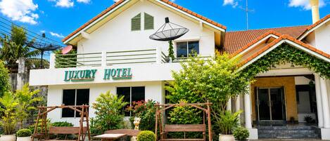 A hotel with a sign reading 'LUXURY HOTEL,' outdoor seating, and a satellite dish.