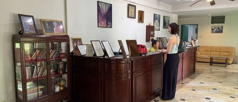 A reception area with a wooden reception desk, framed certificates, and a glass display cabinet with books.