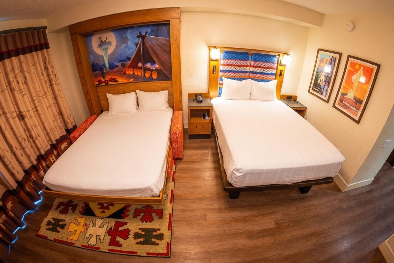 A hotel room with two beds, a nightstand, a painting on the wall, and a rug with a geometric pattern.