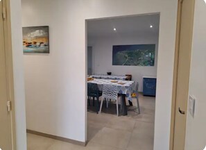 A dining area with a table set for four, a painting on the wall, and a cityscape view. - Family home near the beaches. Pets welcome! (Assérac)