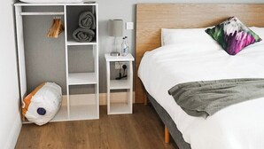 A bedroom with a bed, a nightstand, a wardrobe, and a small table with a lamp.