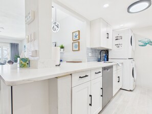 A modern kitchen with white cabinetry, a built-in dishwasher, and a refrigerator. - SoulShine is oceanfront with beautiful sunrises and sunsets in St. Croix! (Christiansted)