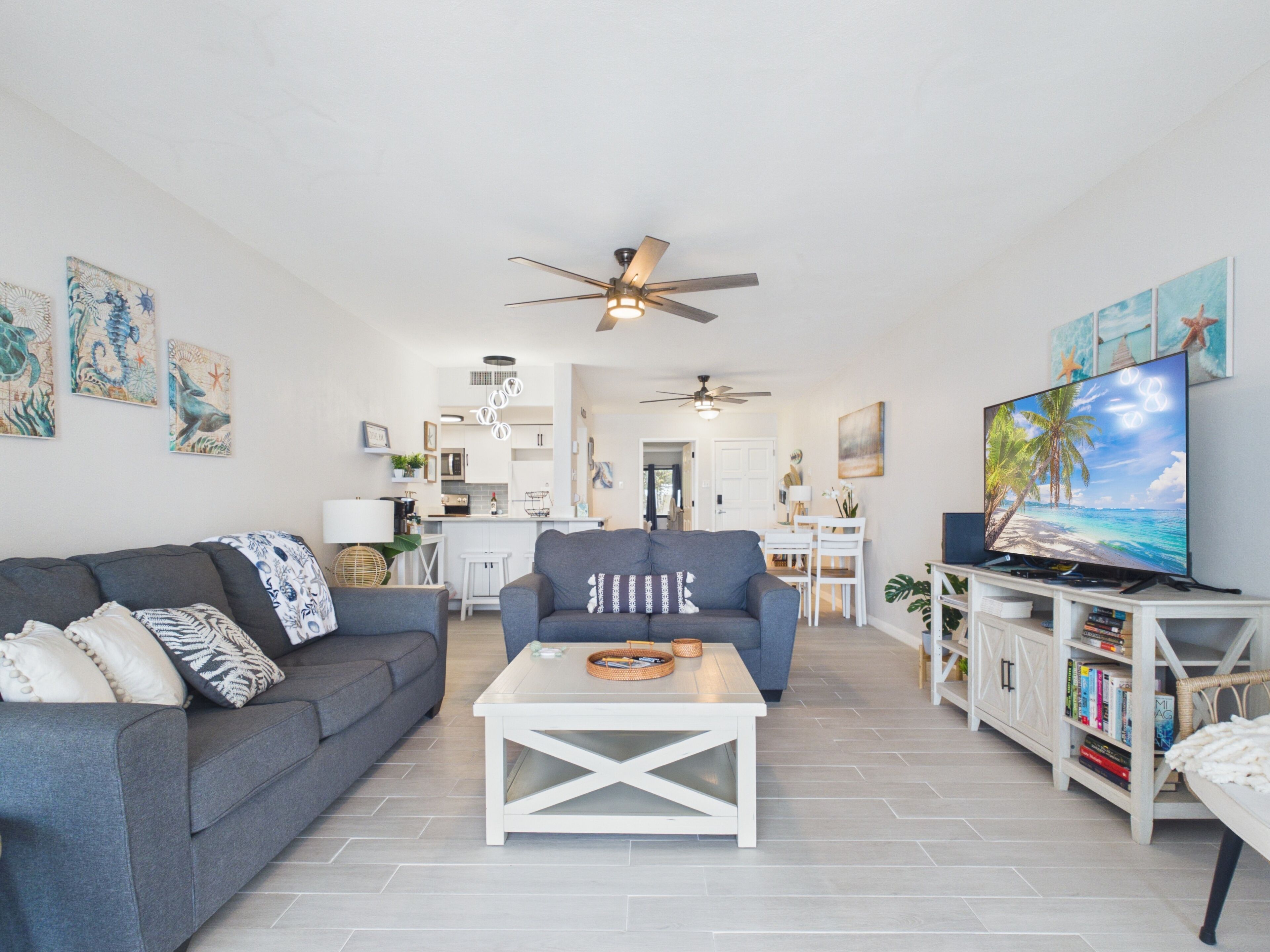 A modern living room with a grey sofa, a white coffee table, and a television on a stand.