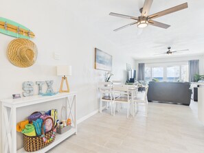 A bright living room with a ceiling fan, a dining area with chairs, a sofa, and a view of the ocean through large windows. - SoulShine is oceanfront with beautiful sunrises and sunsets in St. Croix! (Christiansted)