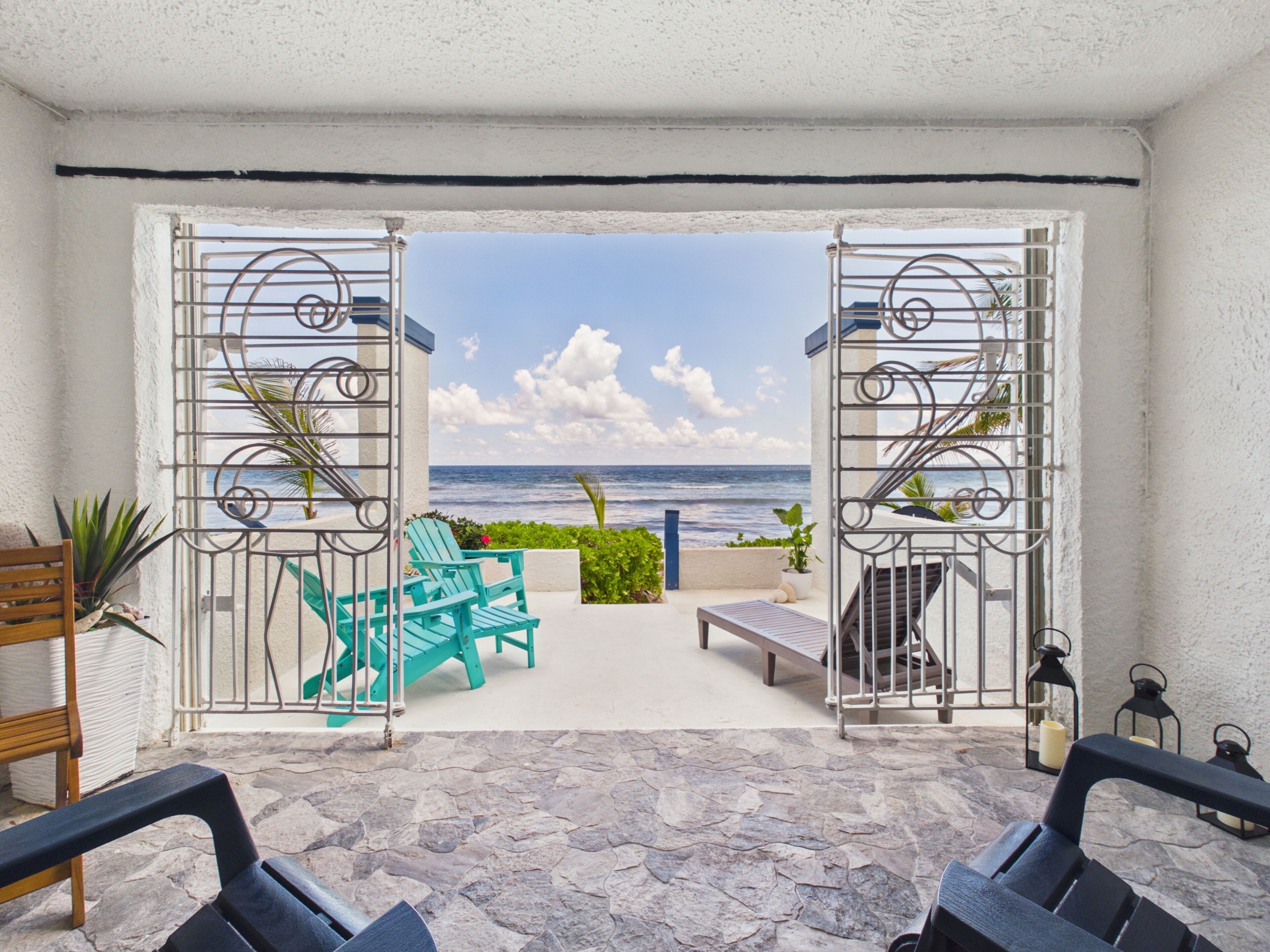 An open patio with a view of the ocean, featuring outdoor seating and a staircase leading to an upper level.