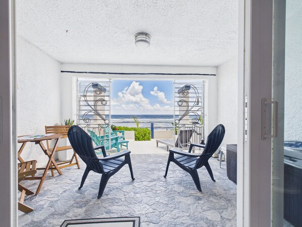 Ein Balkon mit Meerblick, zwei Stühle, ein Tisch und ein Blumentopf.