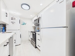 A modern kitchen with white cabinetry, a built-in oven, microwave, and a refrigerator. - SoulShine is oceanfront with beautiful sunrises and sunsets in St. Croix! (Christiansted)