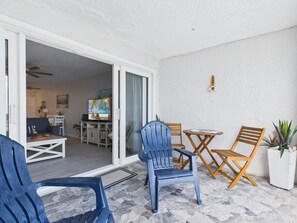 A patio area with a seating arrangement including blue chairs and a wooden table. - SoulShine is oceanfront with beautiful sunrises and sunsets in St. Croix! (Christiansted)