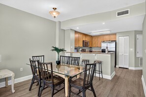 A modern kitchen with wooden cabinets, a stainless steel refrigerator, and a built-in microwave. - Gulf-Front Condo with Balcony Access from the Primary Suite + Steps to Pier Park (Panama City Beach)