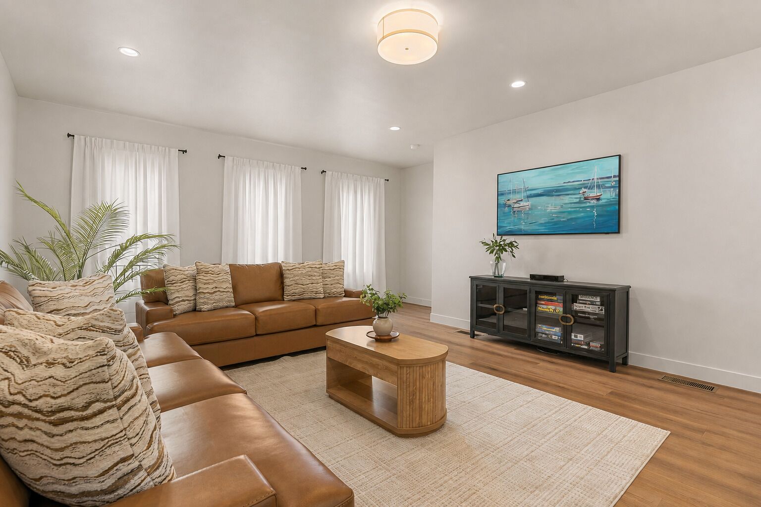 A modern living room with a brown leather sofa, a wooden coffee table, and a large painting of a seascape.