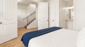Een slaapkamer met een bed, een trap en een badkamer met een spiegel en wastafel.