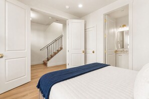 Ein Schlafzimmer mit Bett, einer Treppe und einem Badezimmer mit Spiegel und Waschbecken.