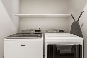 Ein Waschraum mit zwei Waschmaschinen von Maytag und einem Wäscheständer.