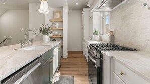Een moderne keuken met een centraal eiland, roestvrijstalen apparatuur en een hanglamp.