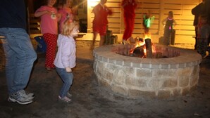 A stone fire pit in an outdoor setting with people around it. - Hilton Head | Couples Island Retreat | Pool + Beach (Hilton Head Island)