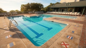 A swimming pool with a diving board, lounge chairs, and a tiled deck with flag patterns. - Hilton Head | Couples Island Retreat | Pool + Beach (Hilton Head Island)
