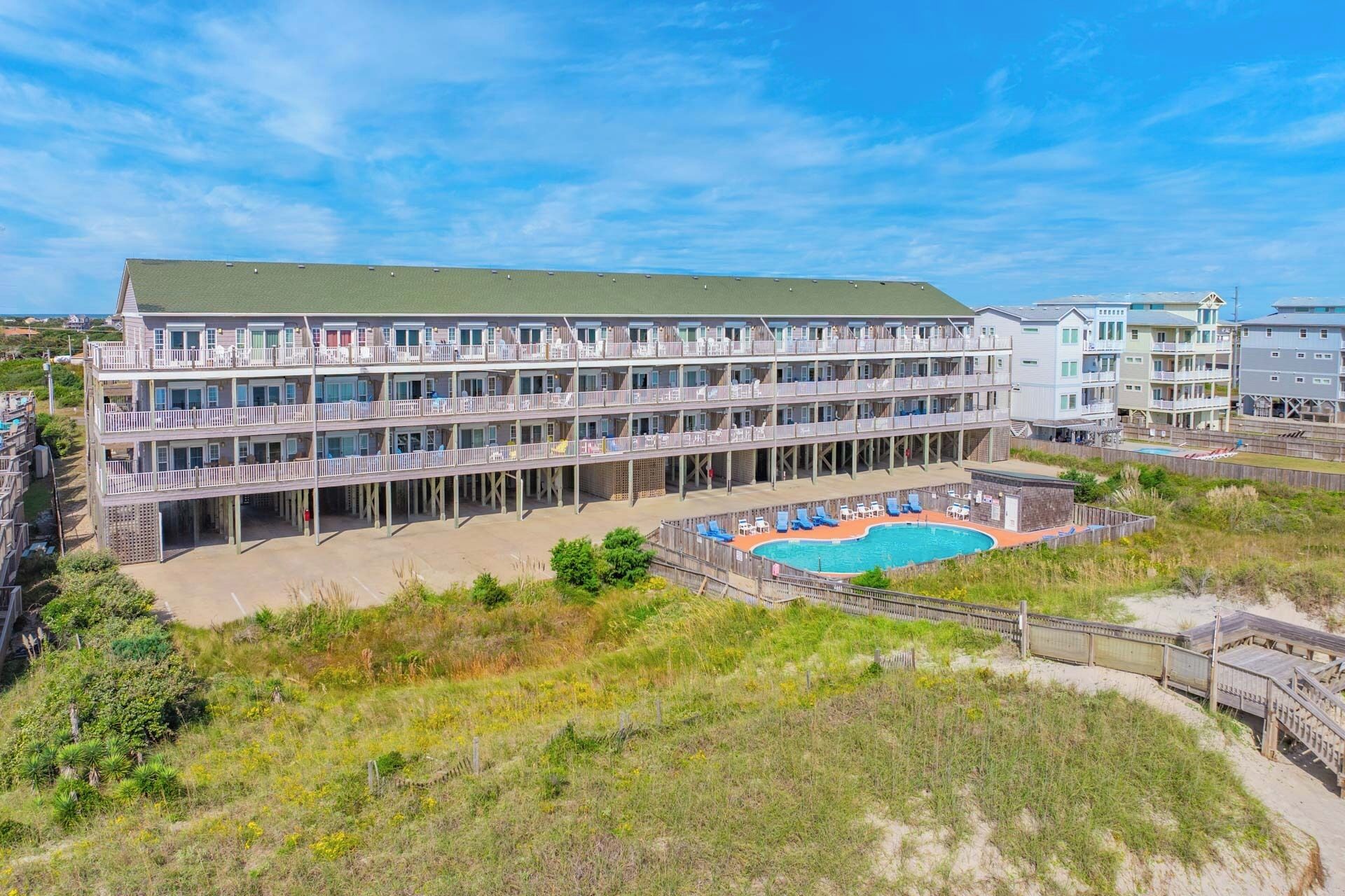 A multi-story hotel with a pool area and beach access.