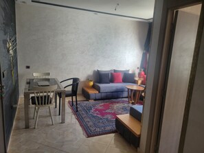 Un salon comprenant un canapé, une table basse, un tapis et un coin repas avec une table et des chaises.