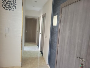A hallway with a patterned wall, a door with a keychain, and a tiled floor. - Welcoming 1-bedroom condo in charming Mohamedia perfect for relaxing (Mohamedia)