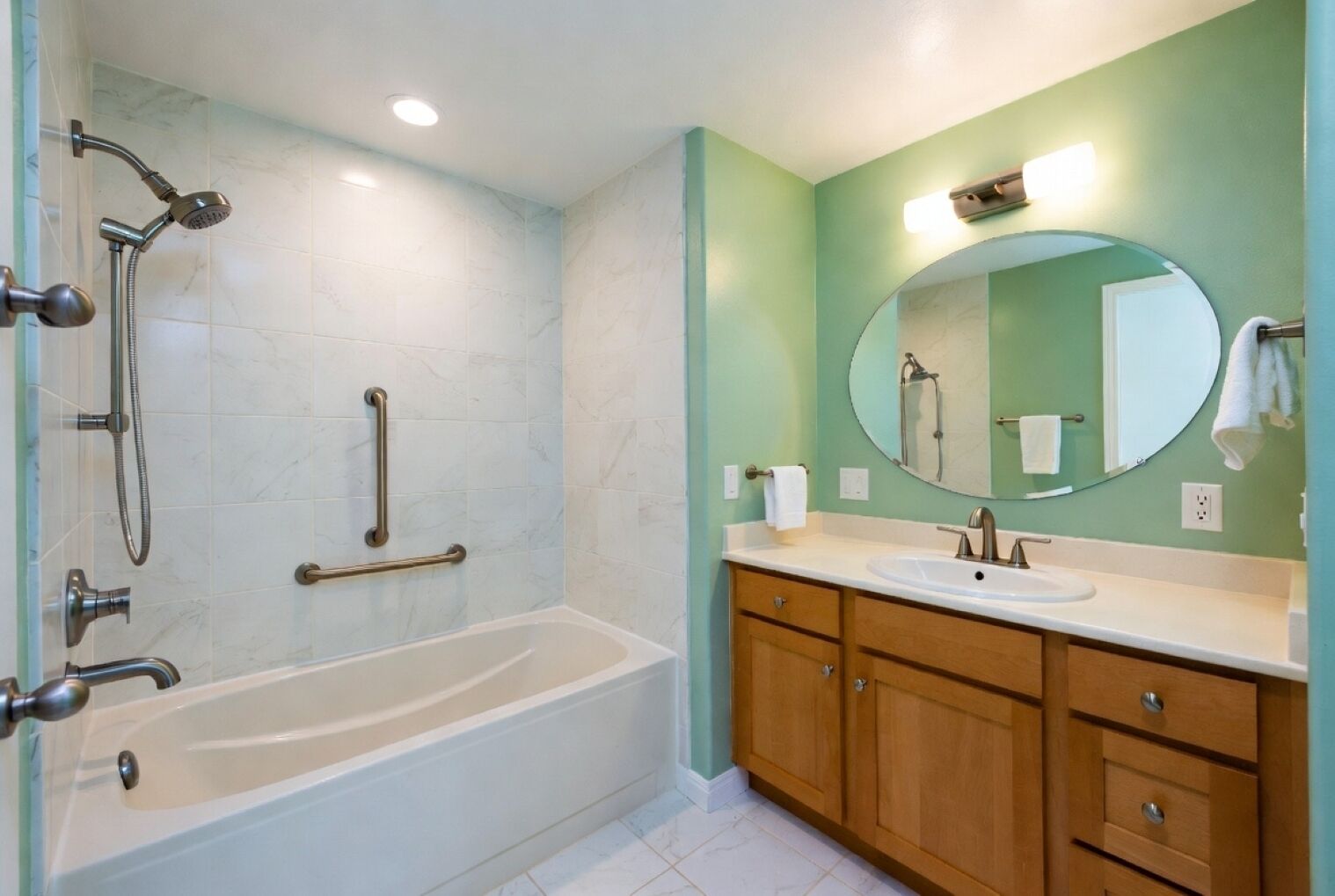 A bathroom with a bathtub, a shower, a vanity with a sink, and a mirror.