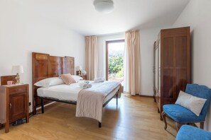 Une chambre à coucher avec un lit en bois, une table de chevet, une chaise et une armoire.