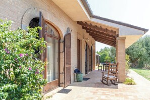 Ein überdachter Patio-Bereich mit Backsteinmauer, Holzläden und einer Pergola.