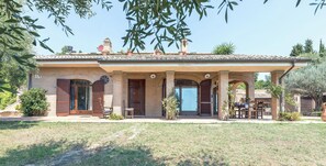 Une maison à deux étages dotée d’un patio couvert, d’une façade en briques et d’une antenne parabolique.