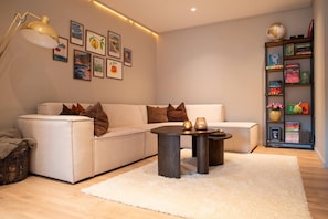 A modern living room with a sofa, a coffee table, and a bookshelf. - North Nest Signature Apartment (Tromsø)