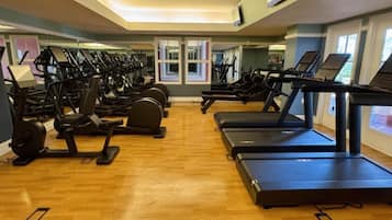Ein Fitnessraum mit mehreren Laufbändern und Crosstrainern, die in Reihen angeordnet sind.