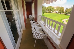 A balcony with white chairs and a view of a green lawn. - Orlando | Relaxed Disney Escape | Pool + Walkable BoardWalk (Lake Buena Vista)