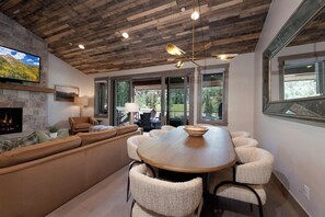 Een modern interieur met een stenen openhaard, een houten plafond en een eetgedeelte met een grote tafel en stoelen.